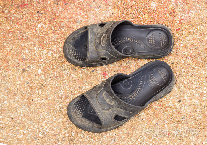 关闭了在石头地板上的旧拖鞋