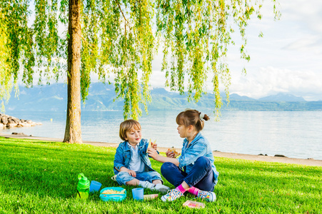 可爱的孩子在一个美好的夏天晚上旁边美丽的湖边野餐