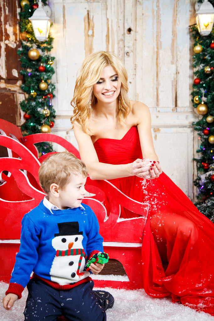 美丽的金发年轻女子，与她在圣诞节背景的小儿子的肖像