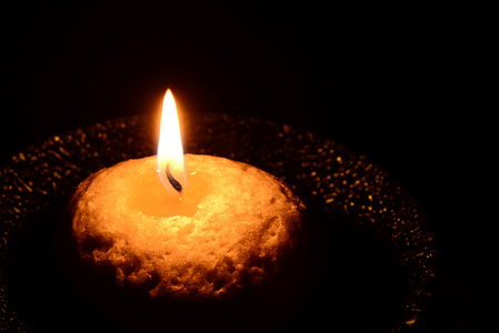 白色的蜡烛燃烧在黑色的背景板上照片
