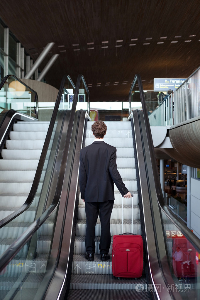在自动扶梯上的行李的人