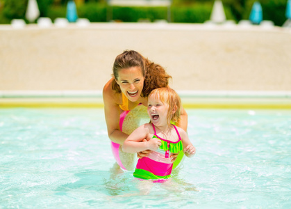 快乐妈妈和小女孩在游泳池里玩