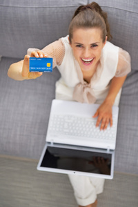 幸福的年轻女人，与笔记本电脑显示信用卡
