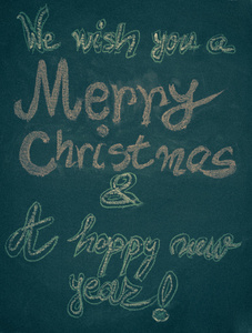 我们祝你圣诞快乐，新年快乐，手用粉笔写在黑板上，老式的概念