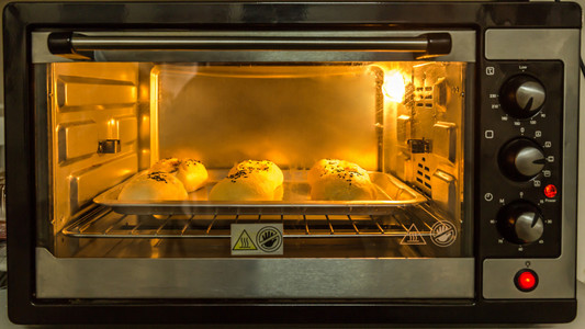 在微波炉里烤的包子面包师傅手里拿着面粉糕点, 面包的面粉过筛碗和