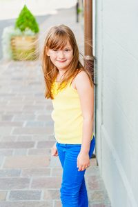 一个可爱的小女孩，穿着黄色的顶部的室外肖像