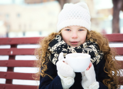小女孩在冰雪覆盖的公园中加热热咖啡寒冷的冬天