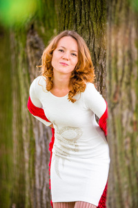 红头发的女孩在树林里的白色连衣裙