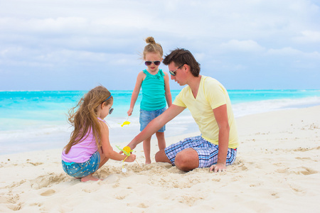 可爱小女孩和热带的白色海滩上的快乐老爸