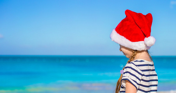 在地处热带的海滩戴圣诞老人帽子的小可爱女孩