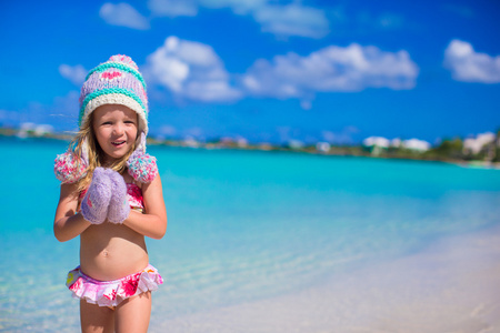 在温暖的针织的帽子和手套在海滩上的小可爱女孩