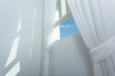 蓝蓝的天空的玻璃窗上的白色窗帘