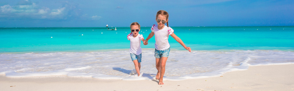 可爱的小女孩在海滩上享受他们的暑假