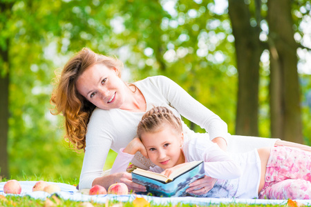 妈妈和女儿读一本书躺在公园里
