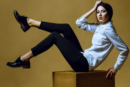 在经典的衣服摆在金背景时尚年轻女孩的画像.完美的头发与皮肤.