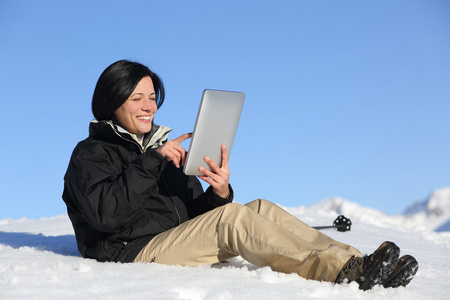 快乐的徒步旅行者女人浏览在雪地上的平板电脑