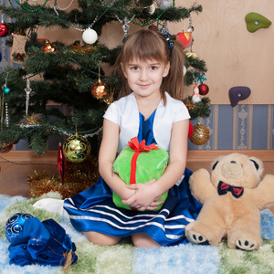 在圣诞树上带圣诞礼物的微笑女孩6年