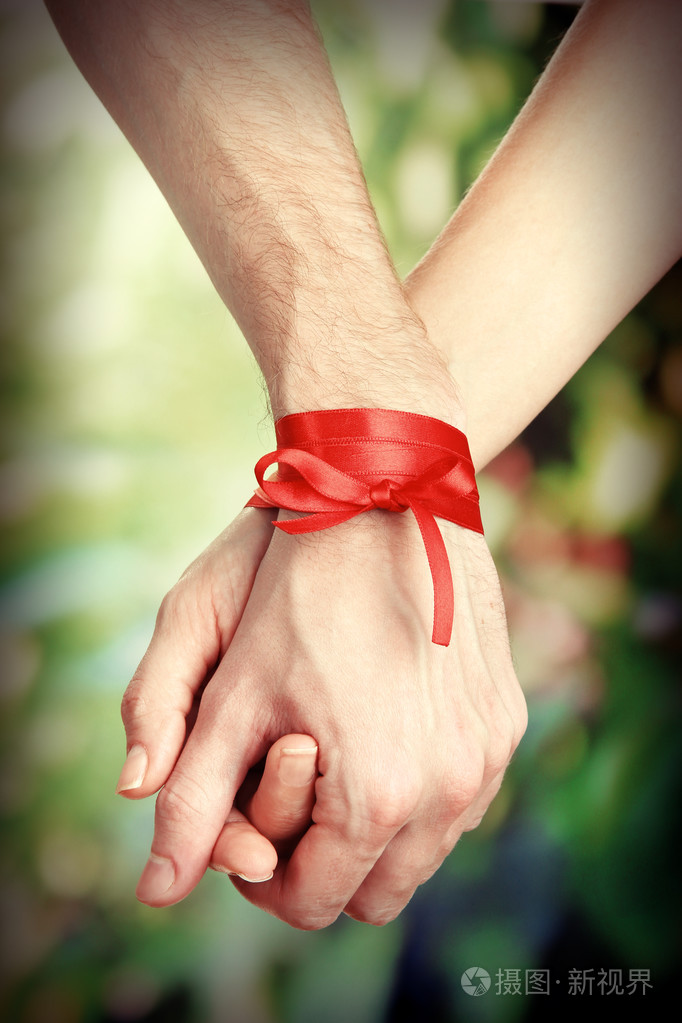 男人的和女人的手绑丝带在明亮的背景上