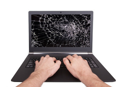 一个破碎的屏幕的笔记本电脑上工作的人
