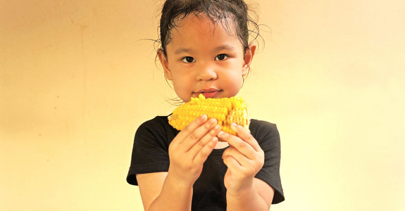 小女孩吃玉米