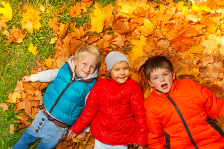 快乐的孩子躺在秋天的落叶