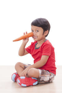 快乐的男孩，用一根胡萝卜。健康食品的概念