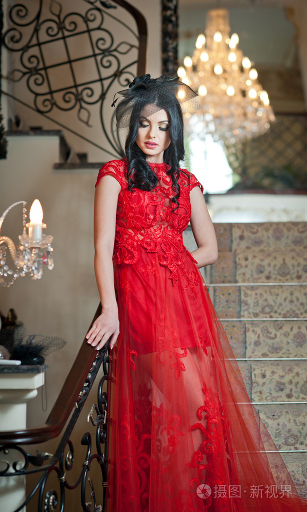 年轻而美丽的女人,穿一件红色的衣服在一家旧旅馆.