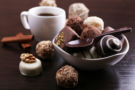 一杯咖啡和一碟用巧克力和甜勺子上深色的木质光滑背景