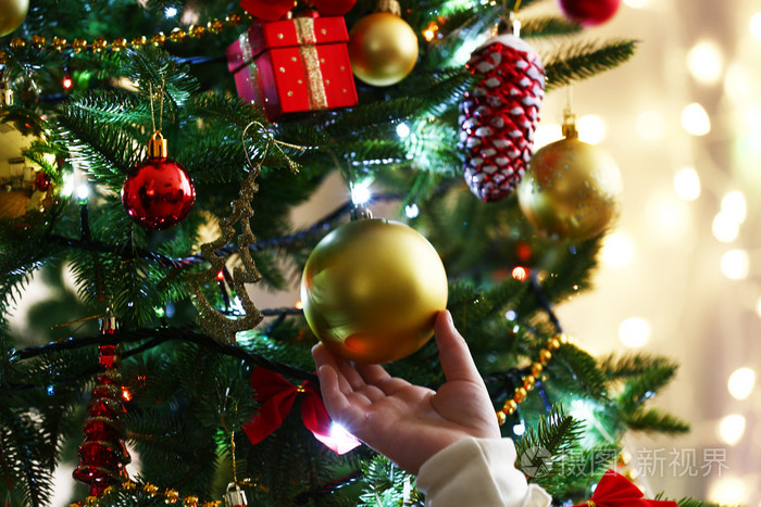 孩子们的双手挂在明亮的背上的圣诞树上