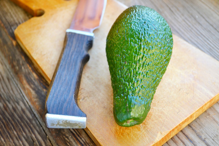 健康绿色的牛油果和木制的桌子上一把刀