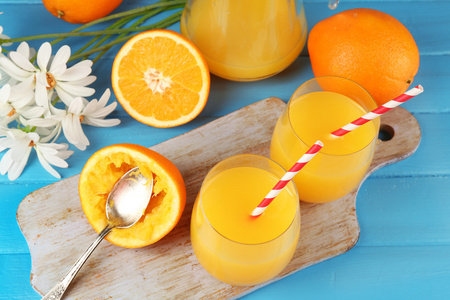 杯橙汁与切片 鲜花和秸秆在砧板上颜色木制背景上