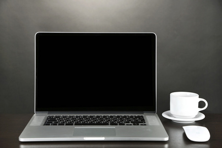 现代笔记本电脑在桌子上，在灰色的背景上