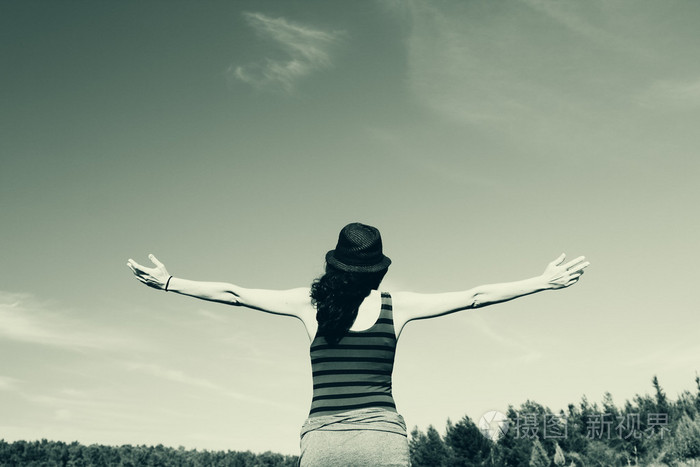 年轻女人张开双臂仰望天空背景