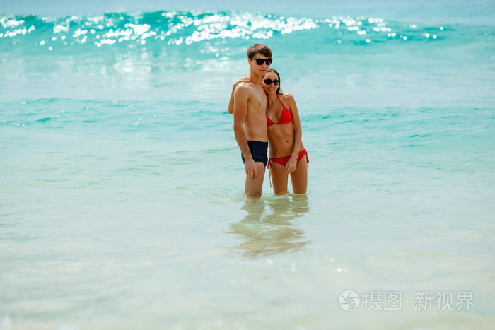 幸福的夫妇在海水中戴着太阳镜