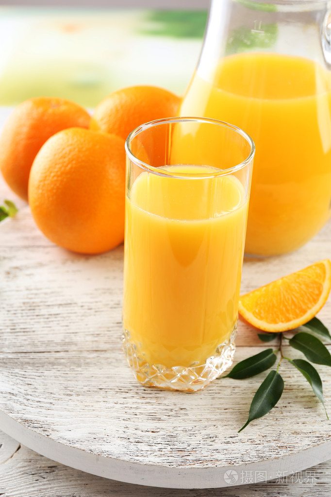 杯桔子汁和橘子色木桌背景