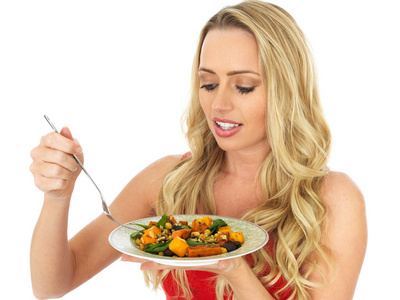 年轻女人吃烤蔬菜沙拉