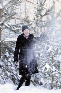 穿着黑色皮大衣的开朗的女人穿着被雪覆盖的别针