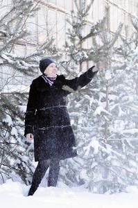 穿着黑色皮大衣的开朗的女人穿着被雪覆盖的别针