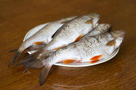 木桌上碗里没有鳞片的新鲜鱼照片