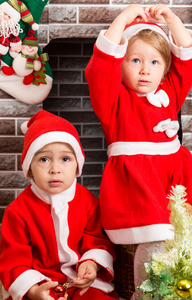 弟弟和妹妹穿着圣诞老人服装的壁炉。圣诞节和新年