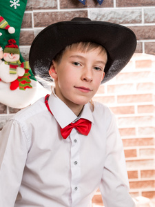 小男孩绅士在壁炉旁的一顶帽子。圣诞节和新年