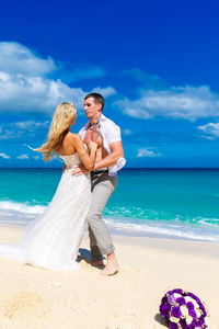 幸福的新娘和新郎在一个热带的海滩上玩耍。婚礼博