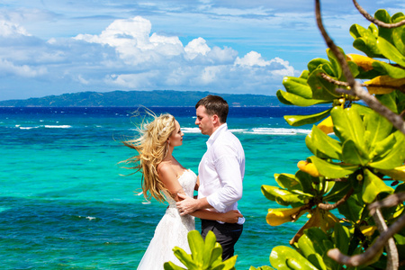 幸福的新娘和新郎在 p 下的热带海滩上玩乐