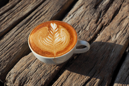 cup 的咖啡拿铁艺术木在复古色调背景上