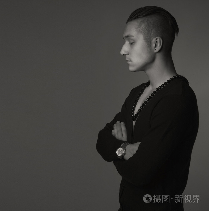 优雅的年轻英俊的男人时髦的发型穿着毛衣和衬衫摆在灰色背景的时尚