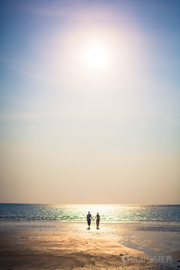 针对海上背景海洋日落的热带海滩上的恩爱夫妻
