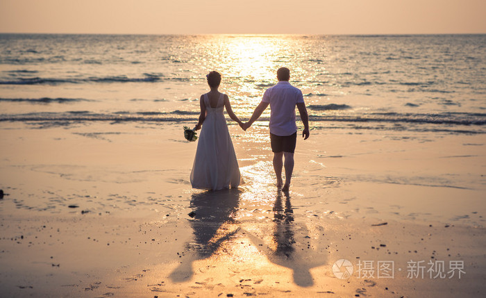 针对海上背景海洋日落的热带海滩上的恩爱夫妻