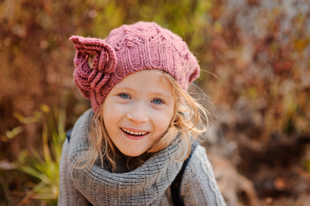 关闭了水平肖像的可爱金发蓝眼睛的孩子的女孩粉红色针织的帽子和灰色毛衣