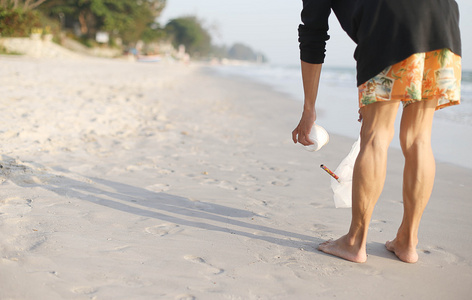 一个男人在海滩上捡起垃圾