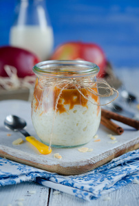 美味的牛奶米饭甜点和焦糖苹果在玻璃罐木桌上